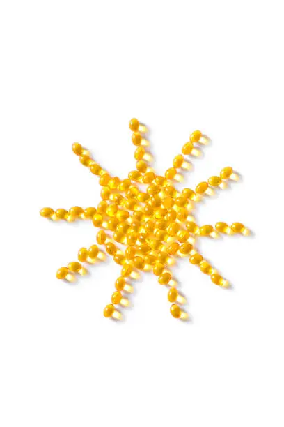 Vitamin D3 capsules (softgels) in shape of sun. Yellow oil softgels isolated on white, top view, copy space.
