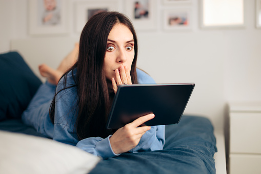 Mujer sorprendida sosteniendo tableta relajándose en casa photo