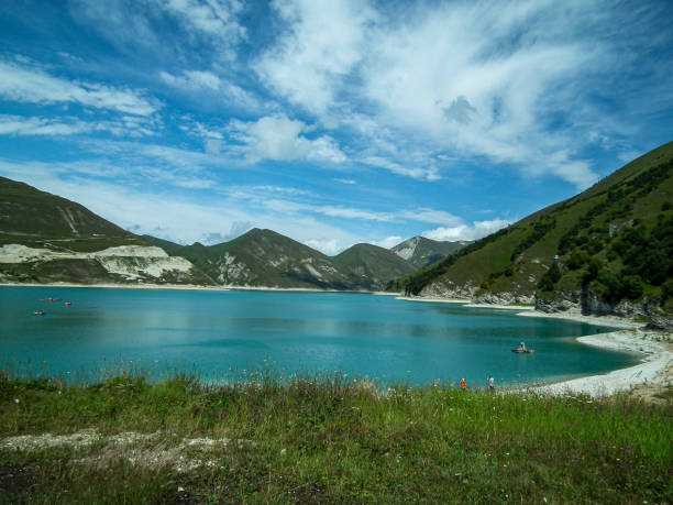 istock Green lake with white shore inside of green mountains 1304527455