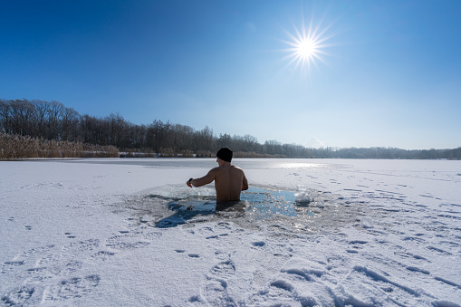 Young man in an ice hole for an ice bath