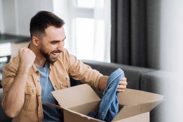 istock Overjoyed happy man unpacked his parcel, happy about getting a long expected order. Caucasian modern guy shopping in internet stores, buying new clothes online, online shopping concept 1304528362
