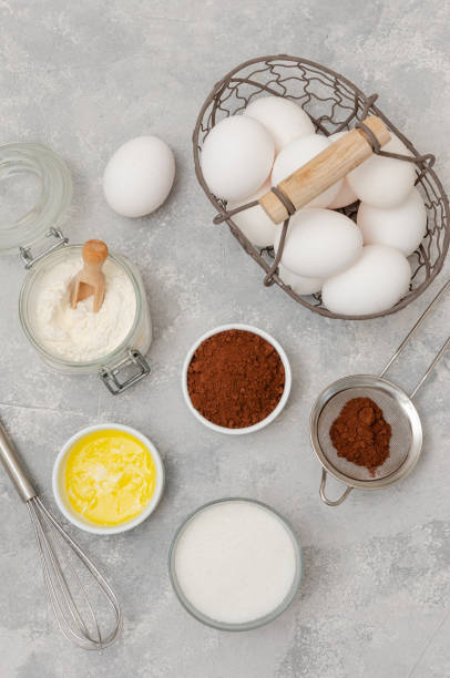 istock Ingredients for making chocolate sponge cake for roll. Eggs, flour, butter, sugar, cocoa on a gray concrete background. Recipe step by step. Top view. 1304528393