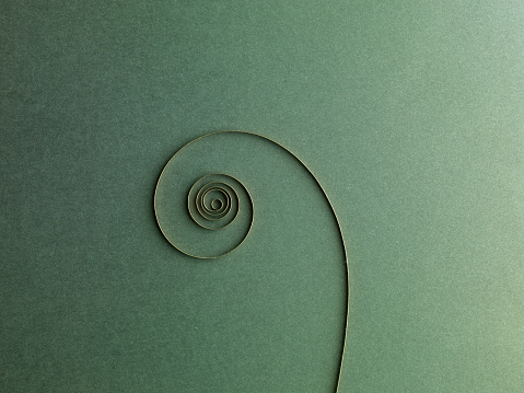 Clock spiral spring abstract. On green paper Background.