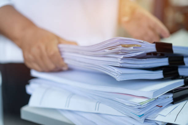 istock Employee checking business unfinished documents with stacks paper files and managing document achieves preparing meeting planing at busy work in financial office. Tax time in filing information 1304529786