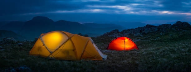 tentes lumineuses chaudes dressées haut sur le panorama sauvage de camp de montagne - langdale pikes panoramic english lake district cumbria photos et images de collection