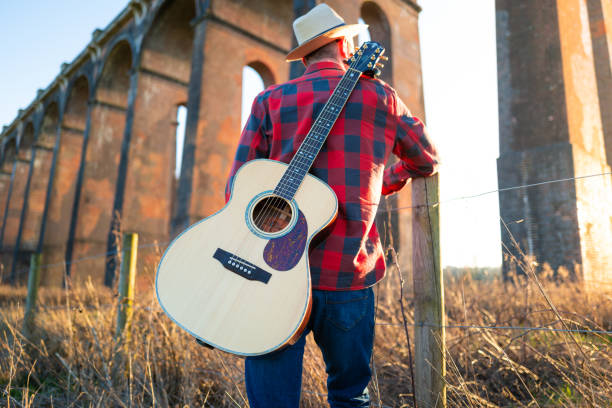 Man wandering in nature at sunset with guitar on his back