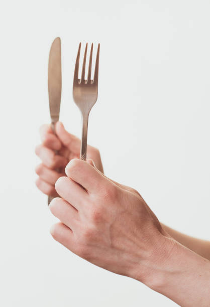 istock Woman hands holding a fork and a knife isolated on a white background 1304533579