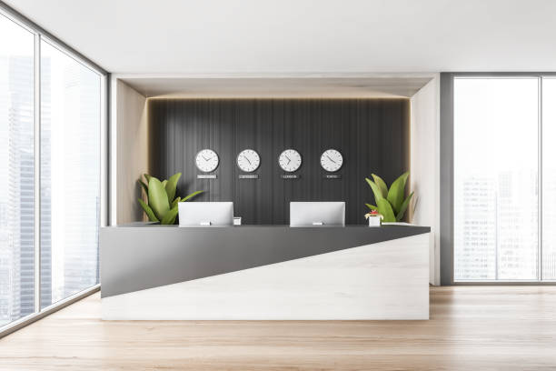 istock Reception room desk with computers and clocks on the black wall near window 1304534252