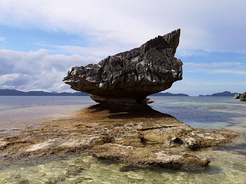 Rock on the shallow transparent waters at the Idyllic Pinagbuyutan island, Bacuit archipelago, El Nido, Palawan.\nPhilippines
