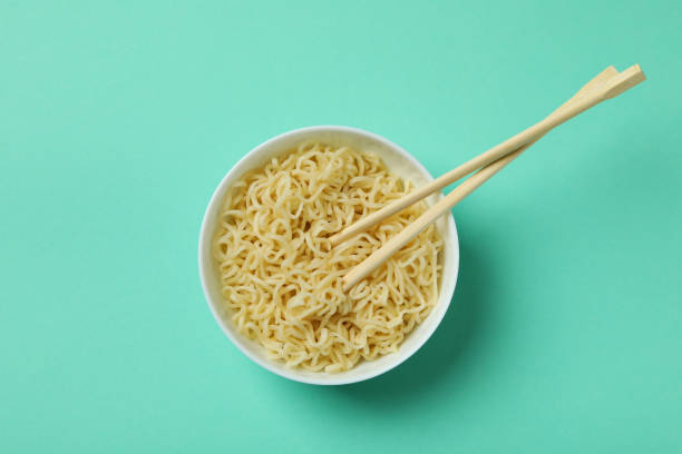 istock Bowl with noodles and chopsticks on mint background 1304536079