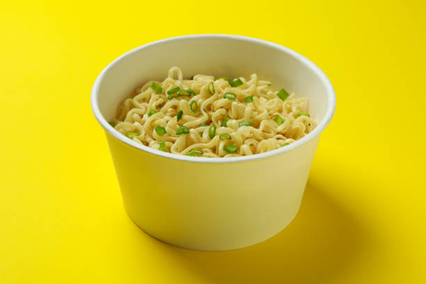 istock Cooked instant noodles in paper cup on yellow background 1304536887