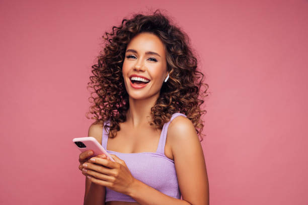 mujer con auriculares inalámbricos sosteniendo smartphone - on the phone women beautiful beauty fotografías e imágenes de stock