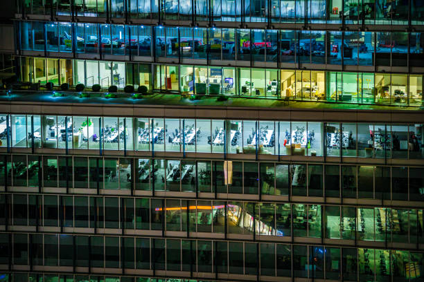Close up of illuminated modern offices during night hours in London City, UK - creative stock photo Close up of highly detailed and illuminated modern offices during night hours in London City, UK, photographed on Canon EOS R full frame system. office window night stock pictures, royalty-free photos & images