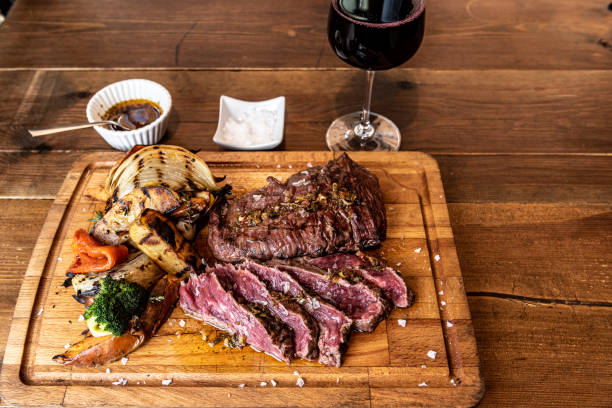 coupe argentine de viande appelée vacio aux légumes et servie sur une planche de bois. - chimichurri horizontal beef steak photos et images de collection
