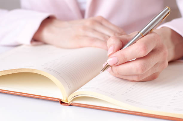 istock a woman writes down information with a pen in a diary 1304541979