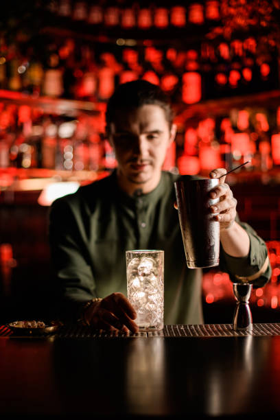 istock glass with ice cubes on the bar and bartender is going to pour cocktail 1304542268
