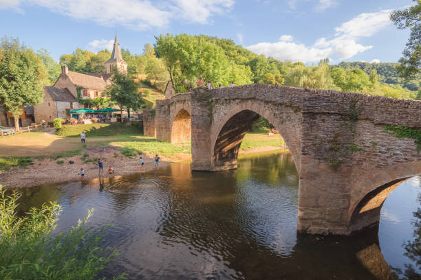 Old stone bridge over the river Aveyron on a summer day in the quaint and charming medieval French village of Belcastel, in Occitanie France.