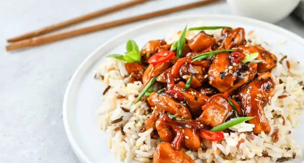 Spicy chicken in sweet and sour sauce with chili pepper. teriyaki chicken's  with  sesame seeds. Chinese cuisine, Thai cuisine. Japanese food, copy space, recipe background, food flat lay