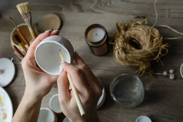 The process of hand-painting a ceramic hand-made bowl. Emphasis on the beautiful female hands of the artist.