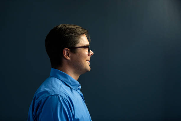 istock Side view smiling young businessman wearing spectacles on dark grey background 1304552252