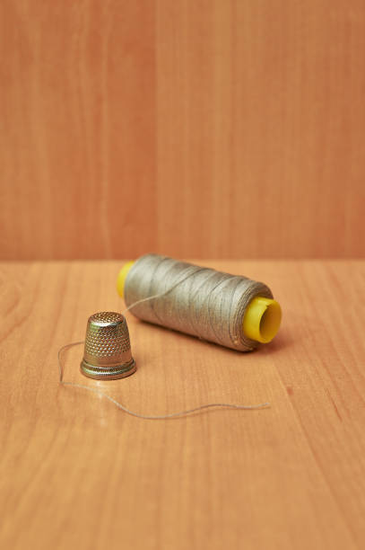 istock Close-up of colorful spool with thimble on wooden table. 1304553469