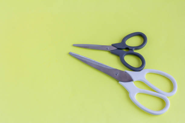 istock Scissors on a yellow background.White large and black small scissors for work and creativity. 1304557291
