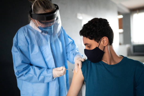 istock Young man being vaccinated at home - wearing face mask 1304557385