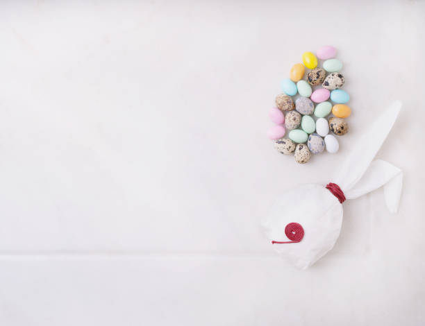 istock Chocolate Easter eggs glazed with pastel coloring and quail eggs over white background. Bunny shaped white baking paper. Happy Easter concept. Copy space. Top view 1304558390