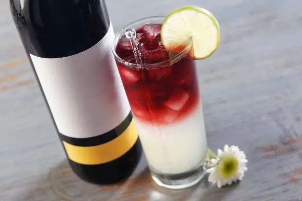 Photo of Sangria cocktail with vodka and red wine garnished with a lemon slice and a small white flower.