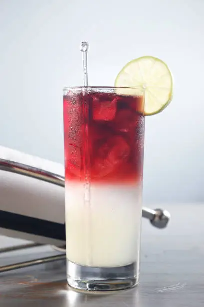 Photo of Sangria cocktail with vodka and red wine garnished with a lemon slice and a small white flower.