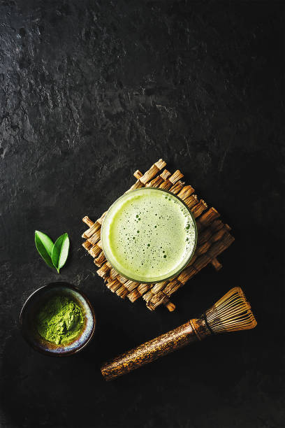 A glass of matcha tea with the ingredients on a dark concrete background with copy space.