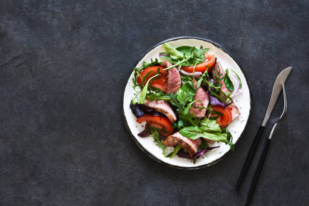 istock Mix salad with tomatoes and medium beef in a plate on a dark background. 1304561416