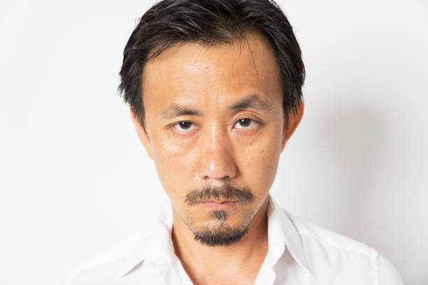 istock Middle aged Asian man serious looking at camera on white background. 1304562866