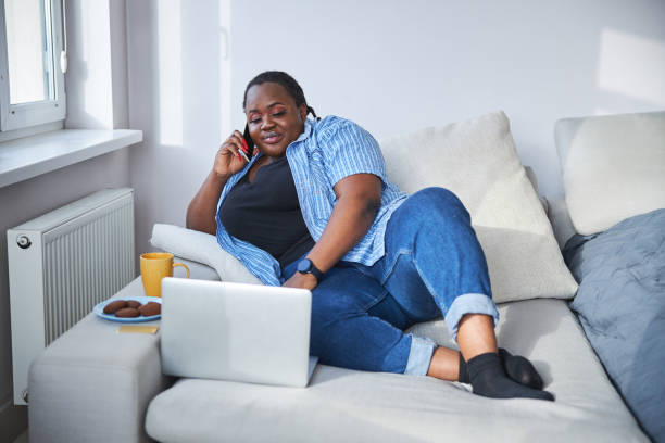 istock Calm lady talking on the phone while sitting on sofa 1304566801