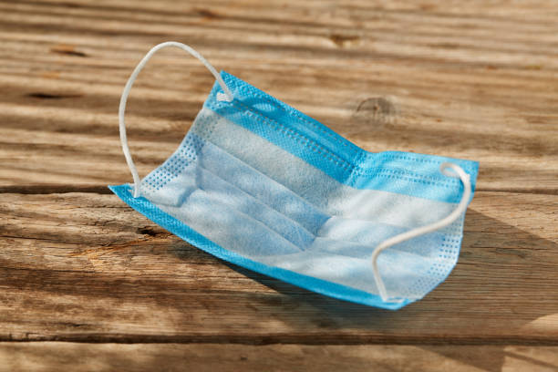 istock Doctor surgical protective face mask on wooden surface 1304567977
