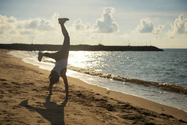 istock athlete woman somersault on beach at sunrise 1304568360