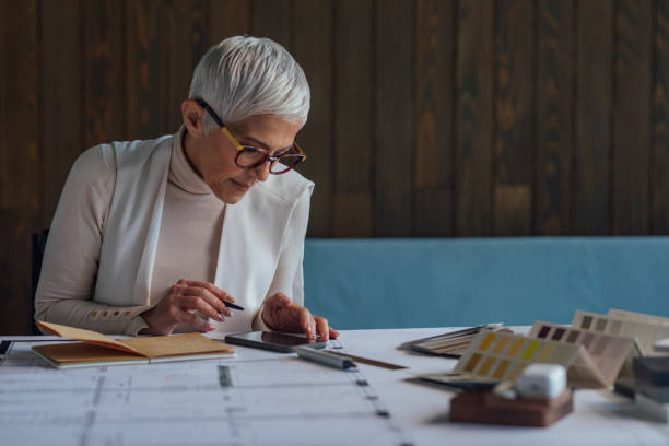 istock Focused Senior Female Architect Using her Smartphone for Inspiration while Working on a Project 1304574808