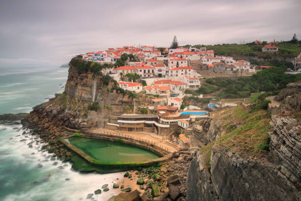 pintoresco pueblo azenhas do mar. casas blancas de vacaciones en el borde de un acantilado con una playa y piscina abajo. punto de referencia cerca de lisboa, portugal, europa. paisaje al atardecer. - azenhas do mar fotografías e imágenes de stock