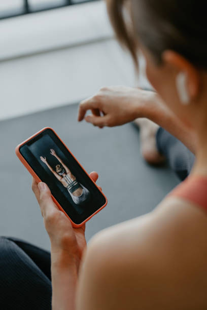 istock Anonymous Woman Picking an Online Workout Program on her Mobile Phone 1304575101