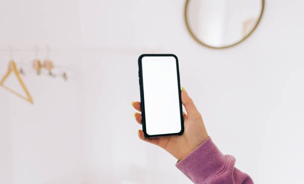 istock Young woman in using smartphone with white screen mock-up in white wardrobe room with floor rack. 1304577979