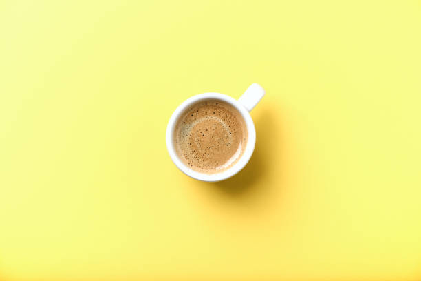 istock Cup of coffee on yellow background. Top view. 1304579434