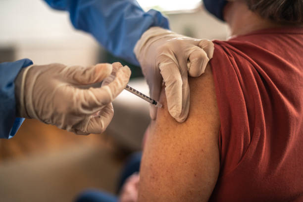 вакцина наносится на руку старшей женщины - doctor medical injection female general practitioner стоковые фото и изображения