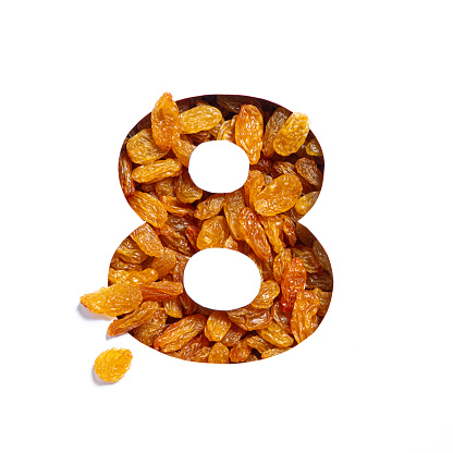 Number eight of raisins and paper cut in shape of eighth numeral isolated on white. Natural typeface of dried berries. High quality photo