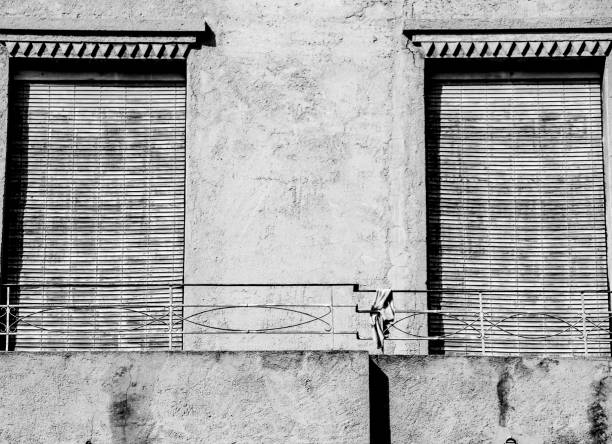 Old house facade with rusty balcony and blind in Spain. Monochrome picture.