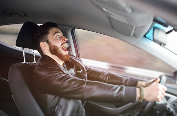 Young man scared at the wheel of a car stock photo