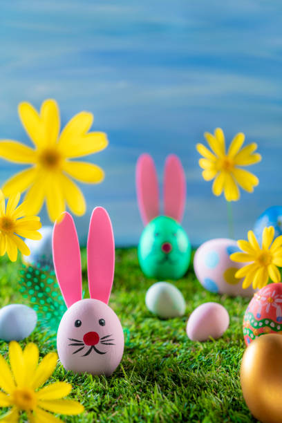 istock Easter eggs in a grass garden and spring daisy flowers
on blue wwtercolor sky 1304591368