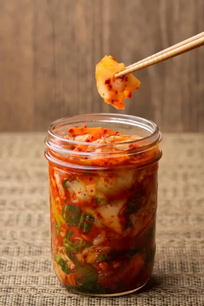 Homemade kimchi in a canning jar with a piece held up with chopsticks.  Healthy probiotic food.