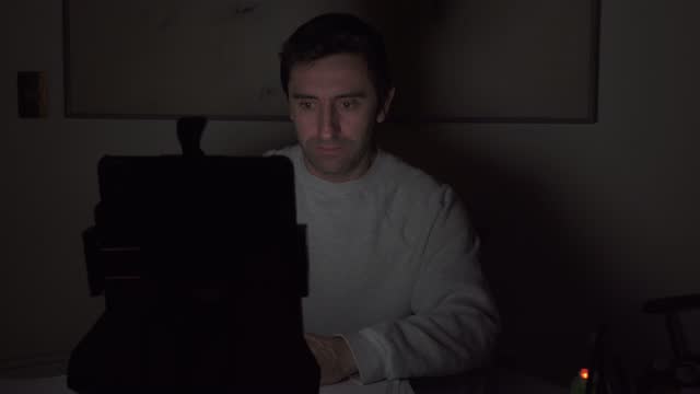 Young man using tablet at night in the dark