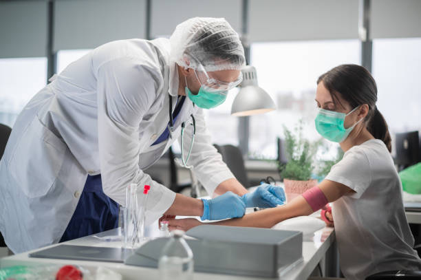 In a private clinic nurse a man puts a tourniquet on the arm of a female patient and takes blood from a vein for analysis stock photo
