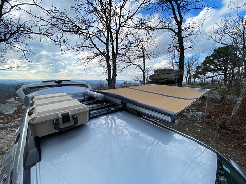 Looking at top of overlanding roof rack on suv with awning and storage container in wilderness